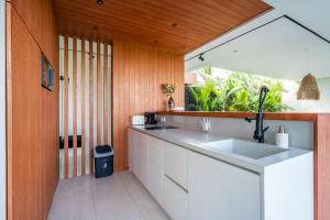 乌布GREEN FLOW Villas Ubud I的厨房设有白色水槽和木墙