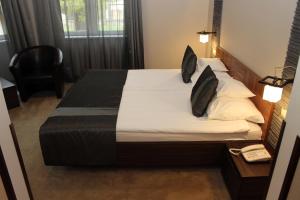 米什科尔茨乐维别墅酒店的一间卧室配有带白色床单和黑色枕头的床。