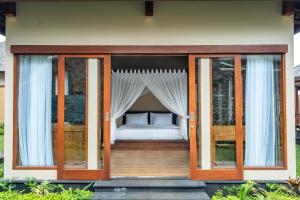 姆杜克Shankara Munduk Bali的卧室设有玻璃门,门廊上设有一张床