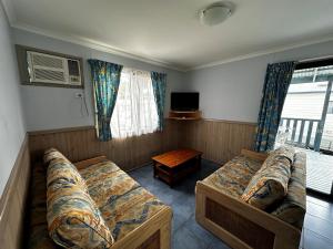 阿勒达拉Big4 Ulladulla Beachside Holiday Park的客房设有两张床、一张沙发和一台电视。
