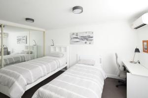 特里格尔Beach Vibe at Terrigal- Stay FOR 3 PAY FOR 2的白色客房的两张床,配有镜子