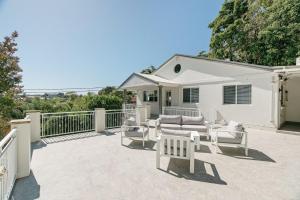 特里格尔Beach Vibe at Terrigal- Stay FOR 3 PAY FOR 2的白色房屋前方的带白色家具的庭院