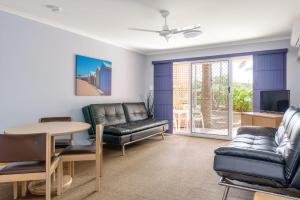 彩虹海滩Rainbow Sands Resort的客厅配有皮革家具和桌子