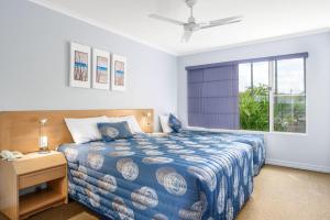 彩虹海滩Rainbow Sands Resort的一间卧室配有一张带蓝色棉被的床和窗户。