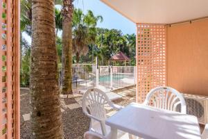 彩虹海滩Rainbow Sands Resort的棕榈树门廊上的白色桌椅