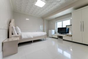 SongjuHotel Gaya的一间白色卧室,配有床和电视