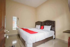KedatonRedDoorz near UBL Lampung 2的卧室配有带红色枕头的大型白色床