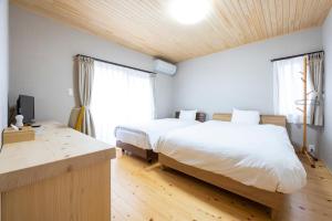福冈Hinoki house的一间卧室设有两张床、一张桌子和窗户。