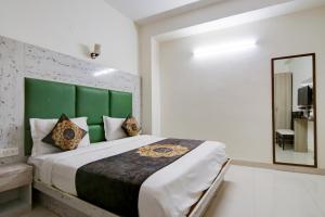 新德里Hotel HSP Suites At Delhi Airport的一间卧室配有一张带绿色床头板和镜子的床
