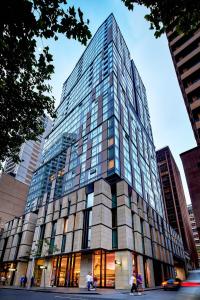 悉尼Meriton Suites Sussex Street, Sydney的一座高大的玻璃建筑,前面的人在步行