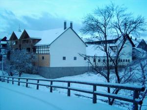 HarbshausenBauernhofpension Büchsenschütz的雪中带围栏的房子