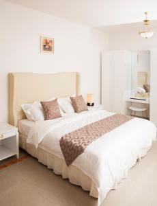 马斯喀特马斯喀特绿洲住处酒店的白色卧室配有一张大床和一张桌子