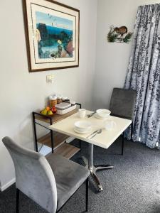 凯塔亚Taipa Views Bed & Breakfast的一张带两把椅子的白色桌子和一张带盘子的桌子