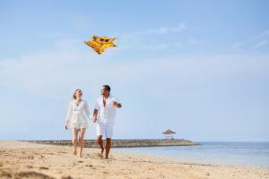 努沙杜瓦巴厘岛努沙杜阿海滩Spa酒店的一名男子和女子在海滩上用风筝行走