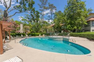 圣西蒙斯岛Harbour Oaks 604的庭院里的一个游泳池,有椅子和树木