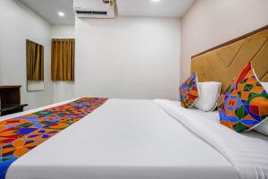 孟买FabHotel New 7 Star的卧室配有一张带彩色枕头的大型白色床。