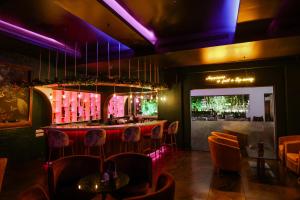 Kumbalgod万德拉度假村的餐厅设有酒吧,配有橙色椅子和紫色照明