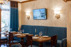 伊万诺-弗兰科夫斯克GANZ HOTEL的用餐室配有2张桌子和1张蓝色沙发