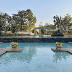 雅加达Senayan Jakarta Oasis - Gym, Pool, Netflix的水中两株盆栽植物的游泳池