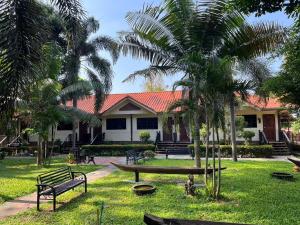 Ban Nong Nam Khan帕雅迈度假酒店的一座公园,在一座建筑前有长椅和棕榈树
