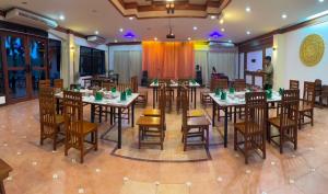 Ban Nong Nam Khan帕雅迈度假酒店的一间设有桌椅的餐厅和一个背景男人