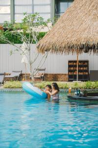 迈考海滩Avani Plus Mai Khao Phuket Suites的游泳池里木筏上的女人和姑娘