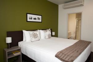 罗托鲁瓦Quest Rotorua Central的卧室配有白色大床和绿色墙壁