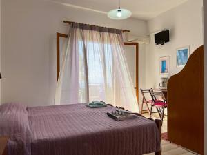 派莱卡斯Anemone的一间卧室配有一张带紫色毯子的床和窗户。