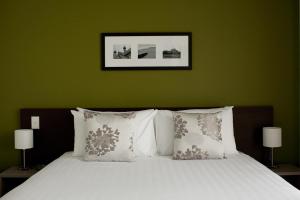 罗托鲁瓦Quest Rotorua Central的一张带白色枕头和绿色墙壁的床