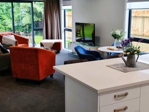 帕拉帕拉乌穆Sunshine Haven - New 3-Bedroom 4-Beds in Paraparaumu的客厅配有沙发、椅子和电视
