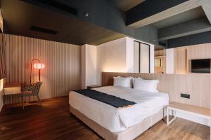 古晋Impiana by Roxy Hotel的卧室配有1张床、1张桌子和1把椅子