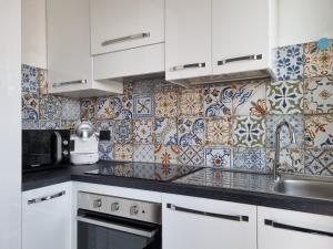阿斯蒂Sesto Piano Apartment的厨房配有白色橱柜和瓷砖墙。