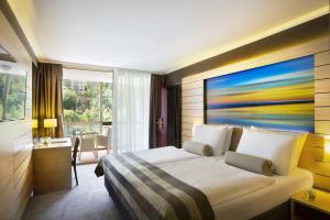 洛夫兰Hotel Excelsior - Liburnia的酒店客房的墙上设有一张带绘画的床铺。