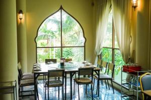 佛统Busaya Resort & Cuisine的一间带桌椅和窗户的用餐室