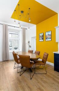 斯特灵The Stylish 3-Bedroom Maisonette Retreat的餐桌、椅子和黄色墙壁