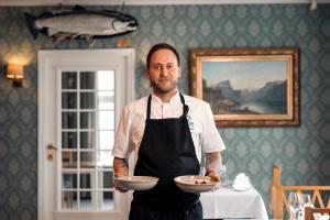 桑纳讷Gloppen Hotell - by Classic Norway Hotels的把两个盘子放在厨房里的人