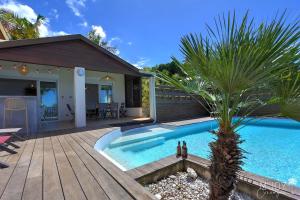 莱萨维龙La KazArmor et sa vue panoramique sur l'océan的一座房子旁的游泳池,里面种着棕榈树
