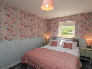 CarinishEala Bhàn Cottage的一间卧室配有一张粉红色花卉壁纸的床