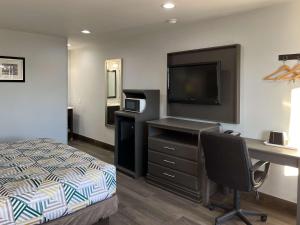 格林维尔Motel 6 Greenville, NC ECU Medical Center的一间卧室配有一张床和一张书桌及电视