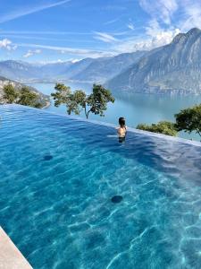 丰泰诺思捷德全景酒店的女人在无边游泳池俯瞰湖泊