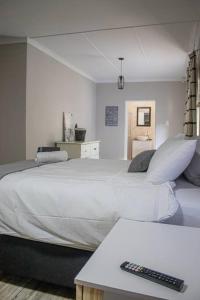 克龙斯塔德House Musantwi的卧室配有一张带遥控器的大型白色床。