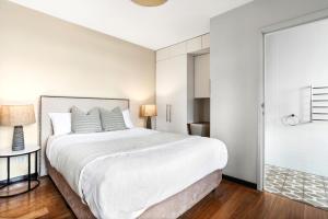 悉尼Balmain Wharf 1 bedroom Apartments的白色卧室设有一张大床和一个玻璃门