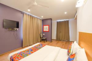 Vibhuti KhandFabHotel Ramayana的一间卧室配有一张床和一台平面电视