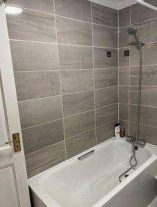 沃特福德Spacious 5 Bedroom House- Harry potter world & London的浴室设有白色浴缸和瓷砖墙。
