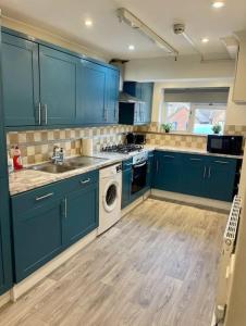 沃特福德Spacious 5 Bedroom House- Harry potter world & London的厨房配有蓝色橱柜和洗衣机。