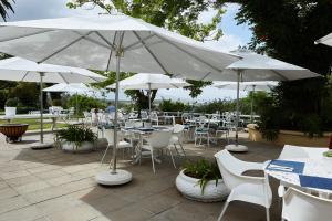 斯泰伦博斯德文郡谷酒店的一个带桌子、白色椅子和遮阳伞的庭院