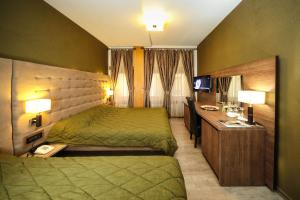 Gjakove卡西亚朱帕弗酒店的一间酒店客房,配有一张绿色的床和一张书桌