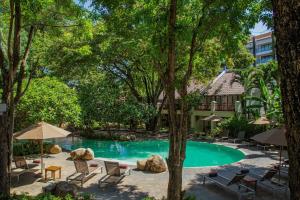 北芭堤雅兀兰酒店芭堤雅度假村的度假村的游泳池,配有椅子和遮阳伞