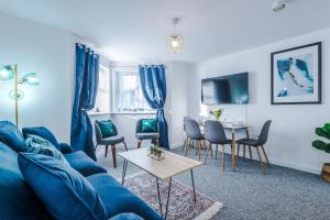 考文垂The Consort Serviced Apartment Coventry的客厅配有蓝色的沙发和桌子