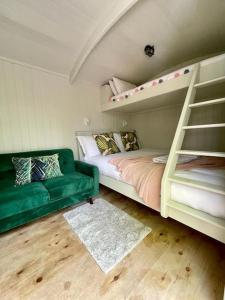 UplymeCosy Shepherds Hut Lyme Regis的一间卧室配有双层床和绿色沙发
